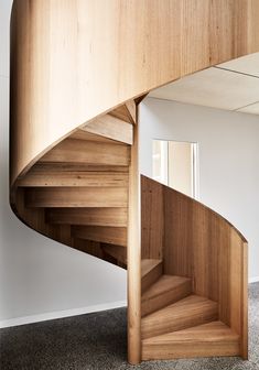 a wooden spiral staircase in the corner of a room with carpeted floor and walls