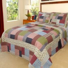 a bed in a bedroom with a colorful quilt on it