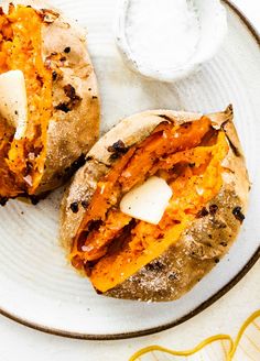 two baked sweet potatoes on a plate with butter