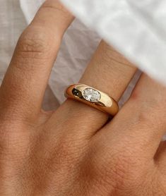 a close up of a person's hand wearing a gold ring with a diamond