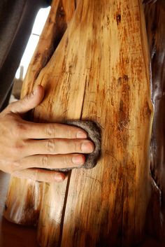 a person's hand on top of a piece of wood