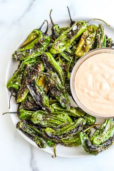 a white plate topped with green peppers next to a small bowl of ranch dressing on top of it