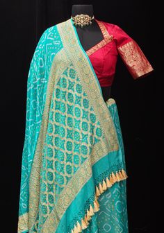 Elevate your ethnic wardrobe with the timeless allure of our Authentic Sarkam Bandhej Silk Georgette Saree in Cyan, adorned with a mesmerizing Zari Border. This saree is a celebration of traditional craftsmanship and contemporary elegance, meticulously handcrafted to elevate your style quotient. Crafted from luxurious silk georgette, this saree features the iconic Sarkam Bandhej technique, where skilled artisans intricately tie and dye the fabric to create exquisite patterns. The serene Cyan hue adds a touch of sophistication and charm, while the shimmering Zari Border exudes opulence and grandeur, making it perfect for special occasions and festivities. The lightweight and flowing georgette fabric drapes gracefully, ensuring comfort and elegance with every movement. Whether it's a wedding Diwali Fitted Pre-draped Saree With Motifs, Traditional Designer Pre-draped Saree For Navratri, Transitional Pre-draped Saree With Cutdana For Traditional Ceremonies, Traditional Fitted Pre-draped Saree For Navratri, Banarasi Silk Sharara With Cutdana, Traditional Georgette Choli With Motifs, Traditional Drape Georgette Choli With Motifs, Transitional Designer Anarkali Set With Bandhani Print, Chanderi Sharara With Bandhani Print