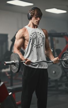 a man with headphones on his ears is holding a barbell in the gym