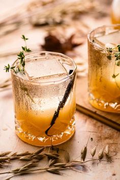 two glasses filled with lemonade and garnished with herbs on a wooden table