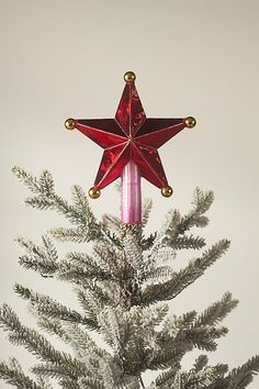 a red star ornament on top of a christmas tree