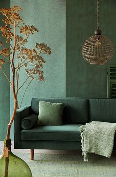 a living room with green walls and a tree in the corner next to a couch