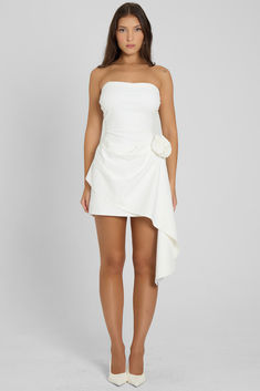 Cut from a opaque, soft and breathable fabric that moves with you, our Rosette Strapless Mini Dress is unlike any other. This white mini dress features a strapless neckline and a bodycon fit that skims down to a mini length. Featuring an asymmetrical hemline in a flowy ruffle design it's complimented by a rosette flower detailing at the hip making it the perfect transitional dress for any day to night look. White Mini Dress With Straight Neckline For Cocktail, White Mini Length Strapless Dress For Cocktail, White Strapless Mini Dress For Cocktail, White Mini Strapless Dress For Cocktail, Flirty White Mini Dress With Straight Neckline, White Fitted Strapless Mini Dress, White Strapless Mini Dress With Ruched Bodice, White Strapless Ruched Mini Dress, White Bodycon Mini Dress With Straight Neckline