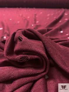 a close up of a red cloth on a bed with water droplets all over it