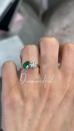 a woman's hand with a diamond and emerald ring