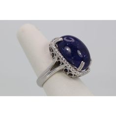 This is part of Chairish’s Fine Jewelry assortment.  WEIGHT: 19.80 grams MAIN STONE: Tanzanite OTHER STONES: Diamonds, 1.25 carats, VVS-SSI clarity, G-H color METAL: 18k white gold SIZE: 6.5 (resizable) CONDITION: New  This Tanzanite Cabochon Diamond Cocktail Ring is impressive as it features a Tanzanite Cabochon weighting in at 34.14 Carats. It has a Diamond surround of 1.25 Carats. This Tanzanite is a gorgeous blue with interesting matrix and is high domed. It is so large you might have to go Elegant Round Sapphire Collectible Ring, Elegant Collectible Round Sapphire Ring, Collectible Elegant Round Sapphire Ring, Dazzling Sterling Silver Gemstones For Formal Occasions, Hallmarked Sapphire Diamond Ring For Formal Occasions, Formal Sapphire Gemstones With Accent Stones, Collectible Sapphire Ring With Center Stone, Collectible Round Sapphire Ring With Center Stone, Exquisite Round Cut Gemstones For Formal Occasions