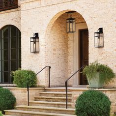 a stone building with steps leading up to the front door and two planters on either side