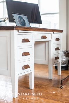 a white desk with drawers and a computer monitor on top