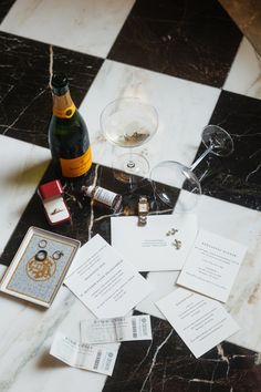 some wine glasses and other items on a checkered tablecloth with a bottle of wine in the background