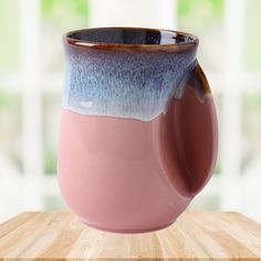 a pink and blue mug sitting on top of a wooden table