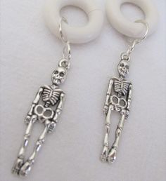 pair of skeleton dangle earrings with white plastic earwires on white fabric background