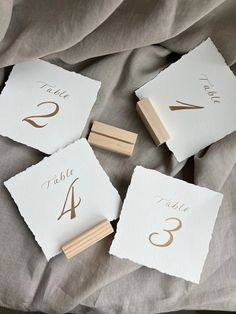 four wooden clothes pins with numbers on them sitting on top of a sheet of cloth