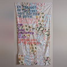 a wall hanging on the side of a building with flowers and words all over it