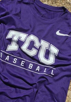 a purple t - shirt with the tcu baseball logo on it is laying on the ground