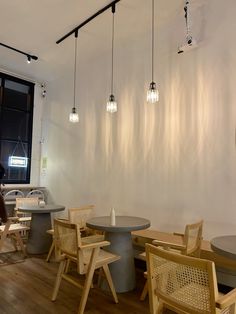 an empty restaurant with wooden chairs and round tables