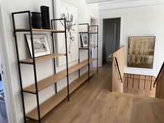 a room with some shelves and pictures on the wall next to a stair case in it