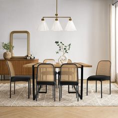 a dining room table with four chairs and a mirror on the wall above it, in front of a window