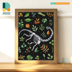 the cross stitch pattern shows a lizard on a black background with orange and green leaves