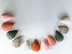 a string of felt hearts hanging on a white wall with some strings attached to them