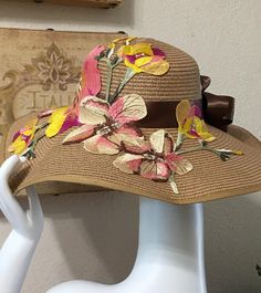 a hat with flowers on it sitting on top of a white mannequin