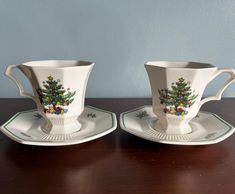 two cups and saucers decorated with christmas trees