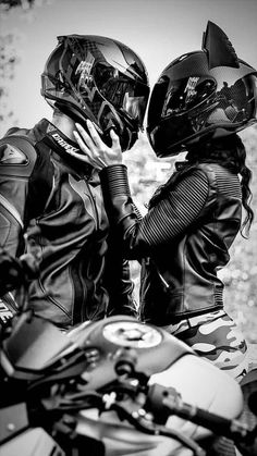 two people in leather jackets and helmets on a motorcycle with their backs to each other