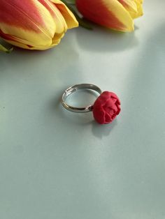 a red flower sitting on top of a silver ring