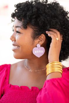 Send hugs & kisses with our XOXO heart earring in light purple. This sweet heart style features XOXO in white text. Designed by Mimi & her sister, all of our earrings are lightweight, hypoallergenic & measures 2"x2". Each earring features soft, acrylic felt backing. Designed in our Creative Studio in Charleston, SC & handmade by skilled artisans. Due to the handmade nature of our beaded styles, each may vary. This listing is for one item. This item is final sale and cannot be returned or exchang Heart Earring, Valentines Earrings, Hugs Kisses, Gifts For Teachers, Sweet Heart, Touch Of Gold, Hugs And Kisses, Earrings Collection, Charleston Sc