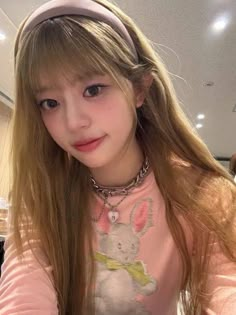 a girl with long hair wearing a pink shirt and headband, posing for the camera