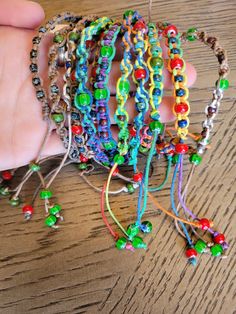 a hand is holding several bracelets with beads