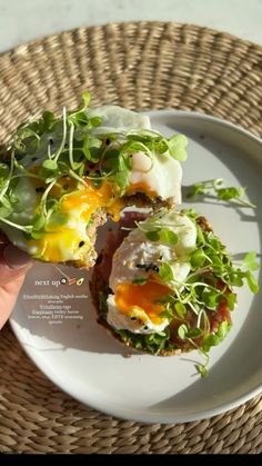 a person is holding an open faced sandwich on a plate with lettuce and eggs