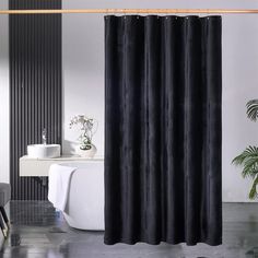 a black shower curtain in a bathroom next to a toilet and sink with a plant on the floor