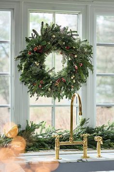 a christmas wreath on a kitchen counter next to a faucet and sink in front of a window