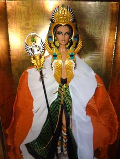 a doll is dressed in an egyptian style outfit and holding a staff with two hands