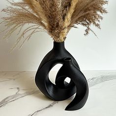 a black vase with some dried plants in it