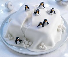 there is a cake with penguins on it and snow balls around the edges that are white