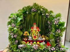 an arrangement of fruits and vegetables on display in front of a ganeshi idol