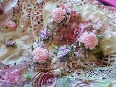 some pink flowers are laying on a lace doily with beads and chains around them