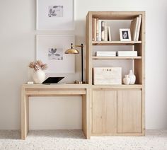 a wooden desk sitting next to a book shelf with books on top of it in front of a white wall