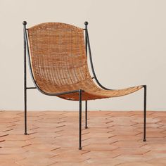 a wicker chair sitting on top of a wooden floor next to a brick wall