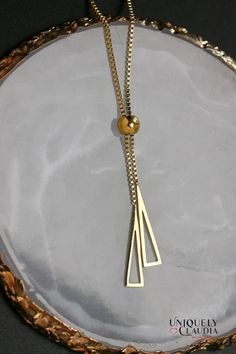 This delicate Stainless Steel Pyramids Lariat Goldtone Necklace will bring a touch of elegant sophistication to your look. It features two triangle pendants elegantly suspended from a delicate gold-toned chain. Perfect for any occasion, this necklace is sure to become your go-to piece! The geometric design of the triangle pendants catches the light in all the right places - making it perfect both day or night. Add a touch of glamour with this stylish accessory, wear it on its own or layered with Minimalist Gold-tone Lariat Necklace With Delicate Chain, Minimalist Gold-tone Lariat Necklace With Adjustable Chain, Gold-tone Minimalist Lariat Necklace With Adjustable Chain, Minimalist Gold Y-shape Lariat Necklace, Minimalist Gold-tone Lariat Necklace, Minimalist Gold-tone Gold-plated Lariat Necklace, Elegant Gold Triangle Necklace, Minimalist Gold Drop Necklace For Party, Gold Minimalist Metal Lariat Necklace