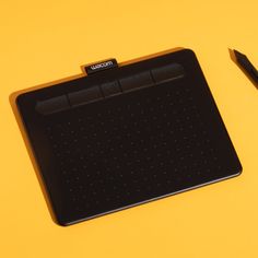 a pen and tablet sitting on top of a yellow surface