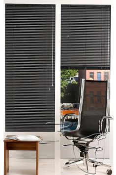 an office chair sitting in front of a window with blinds on the windowsills