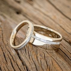 two wedding rings sitting on top of a wooden table