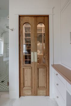 an empty bathroom with two wooden doors and white tile flooring in front of it